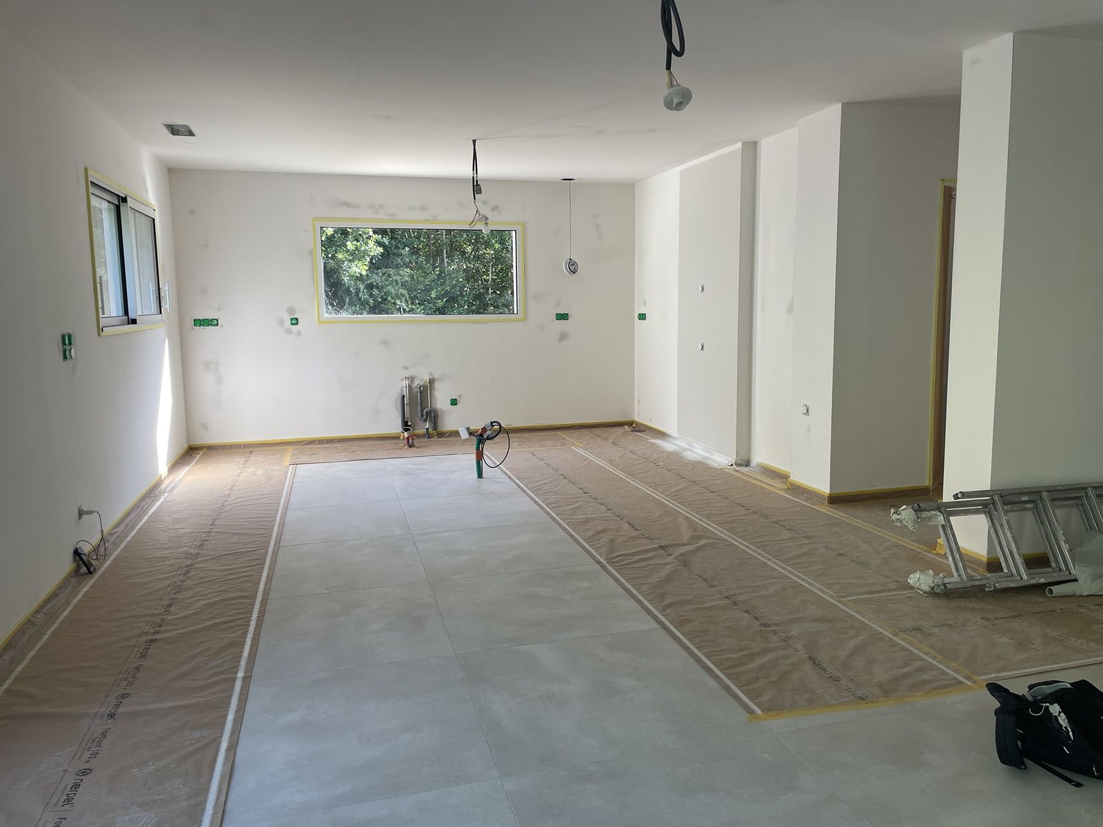 Sols et menuiseries d’une maison neuve entièrement protégés par du papier et du ruban avant les travaux