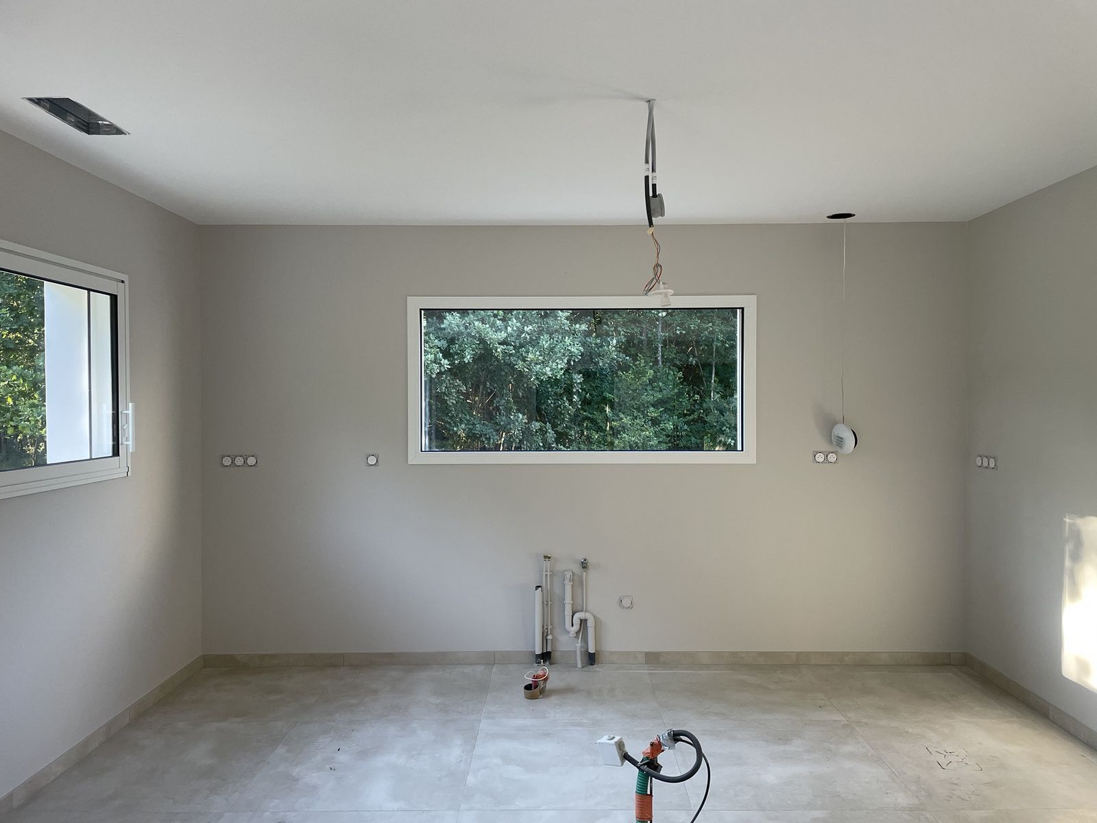 Pièce terminée : murs et plafonds peints d’une teinte uniforme, fenêtre horizontale sur la verdure
